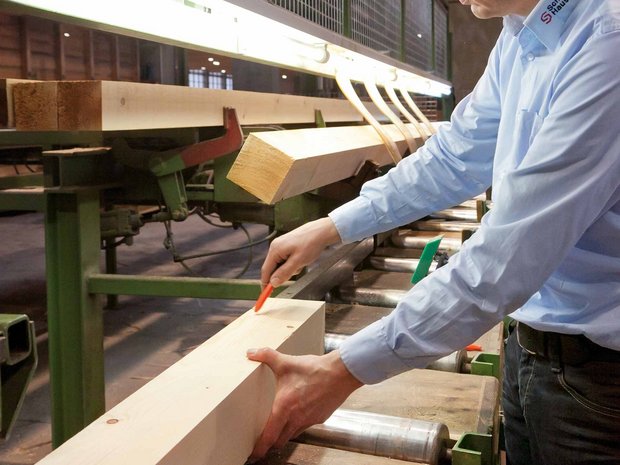[Translate to Französisch:] Messung und Anpassung von Holz durch Person in der Produktionshalle der SchwörerHaus KG